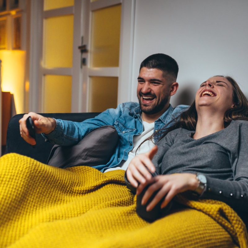 stock-photo-romantic-couple-laying-sofa-in-their-living-room-watching-movie-on-television-1615108387